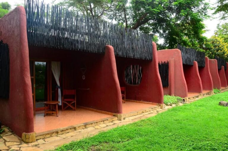 Las terrazas de las habitaciones del Amboseli Serena Safari Lodge, entre muros rojos redondeados, frente a un césped