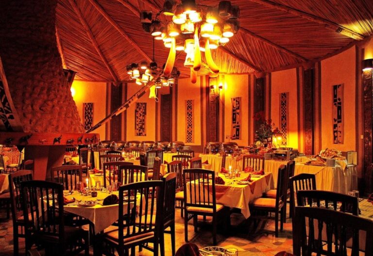 El comedor del restaurante por la noche, con mesas de manteles amarillos y lámparas de araña encendidas