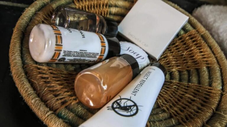 Una cesta trenzada llena de productos de bienvenida, entre ellos un repelente de insectos