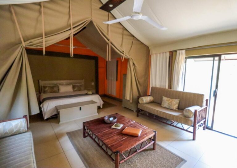 El interior de una tienda, con una cama grande, un sofá, una mesa baja de madera y un gran ventanal