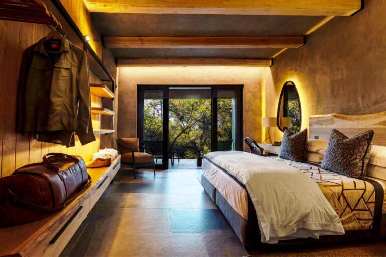Una suite con cama grande, abierta a una terraza entre los árboles