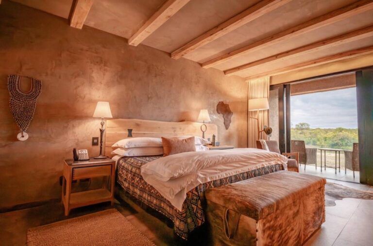 Una suite con cama grande, un mapa de África de madera en la pared y una terraza sobre la sabana