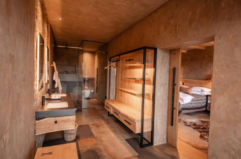 El baño de una suite, con ducha acristalada, lavabo y armario abierto