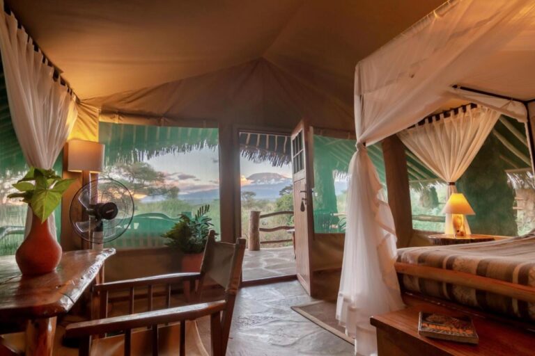 Una tienda del Kibo Safari Camp abierta a su terraza, con el Kilimanjaro a lo lejos al atardecer