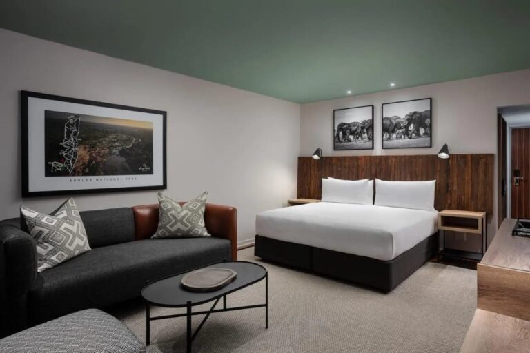 Una habitación Deluxe con una cama grande y un sofá, en el Kruger Gate Hotel