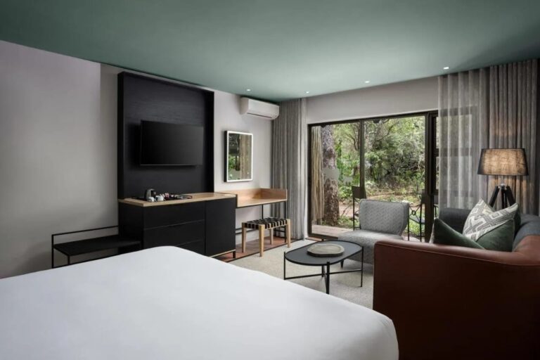 Una habitación Deluxe abierta a los árboles por un gran ventanal