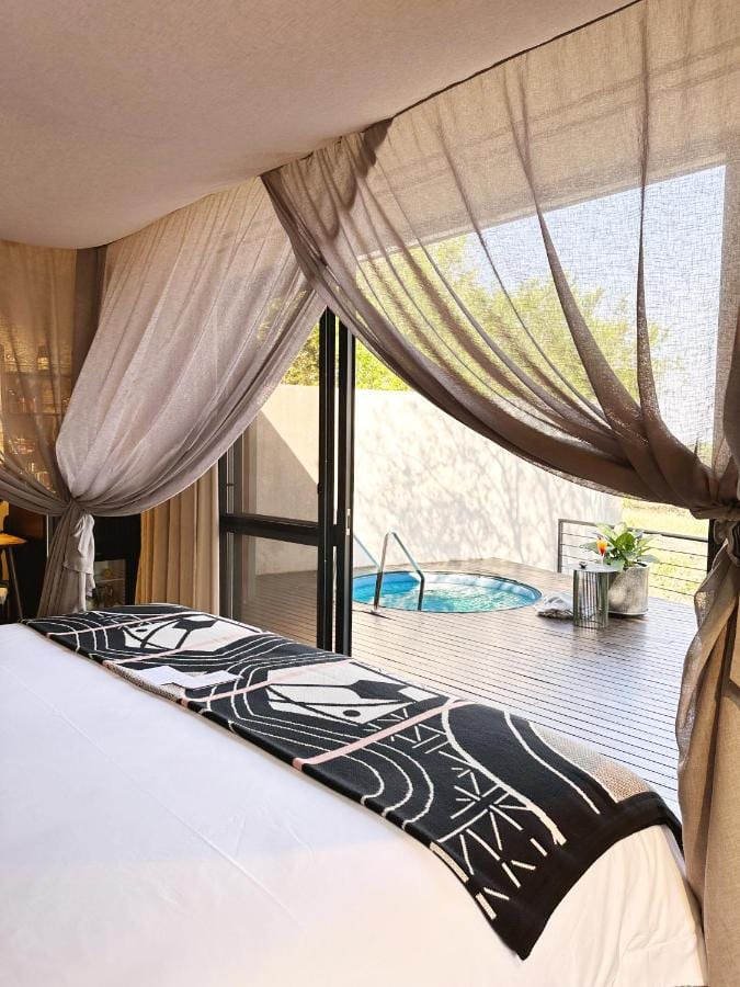 Una suite del jardín, con la cama bajo visillos, abierta a una terraza de madera y a su pequeña piscina redonda