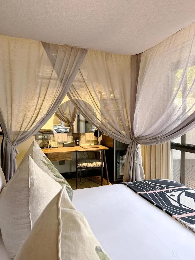 La zona de escritorio de una suite, vista desde la cama rodeada de visillos