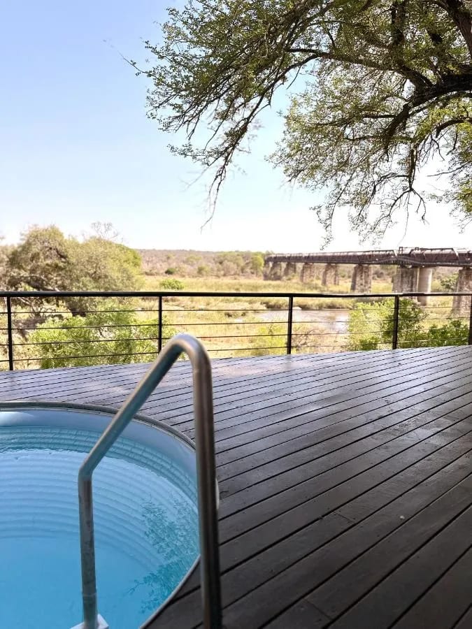La pequeña piscina de una suite frente a la sabana, con el puente y el tren a lo lejos
