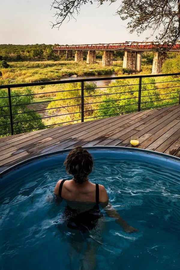 Una mujer en la pequeña piscina de una suite, frente al tren sobre el puente