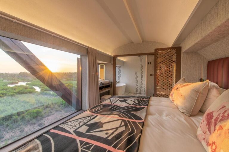 El interior de un vagón del Kruger Shalati, con la cama frente a una gran ventana al río y la bañera al fondo