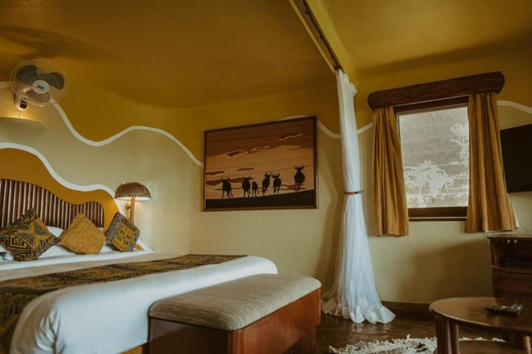 Una habitación con un cuadro de siluetas de ñus sobre la cama y un ventilador de pared