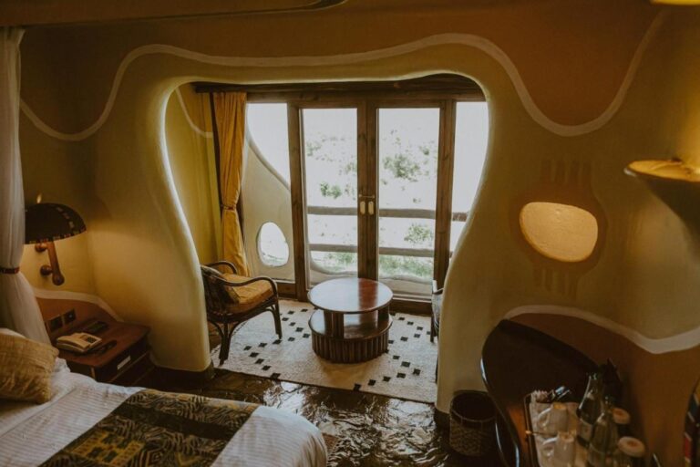 Una habitación de paredes curvas del Mara Serena Safari Lodge, con una zona de estar delante de la puerta acristalada del balcón