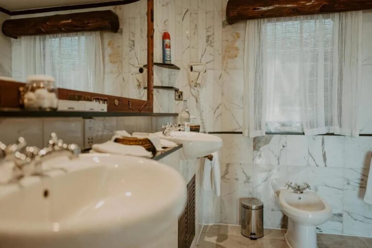 Un lavabo en primer plano en un baño de mármol, con un bidé al fondo