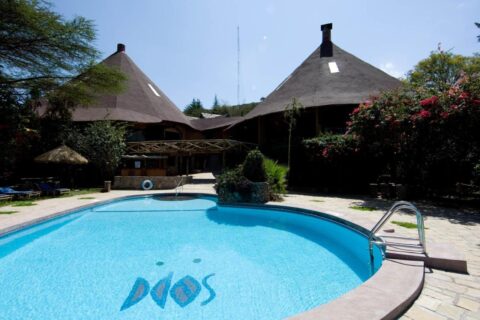 La piscina del Mara Sopa Lodge, delante de edificios con grandes techos cónicos de paja
