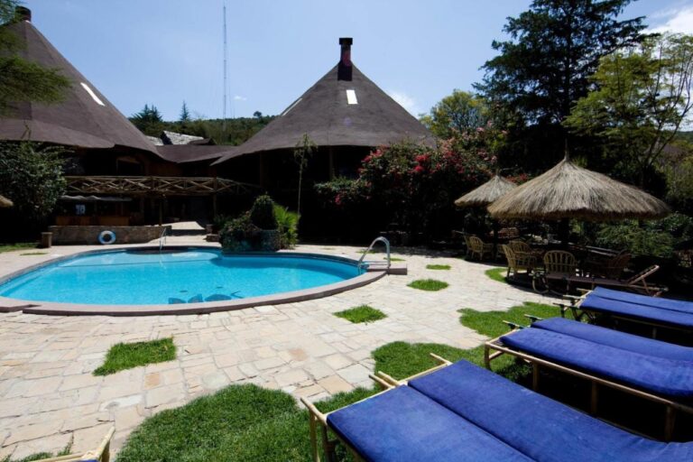 Tumbonas con cojines azules al borde de la piscina, junto a sombrillas de paja