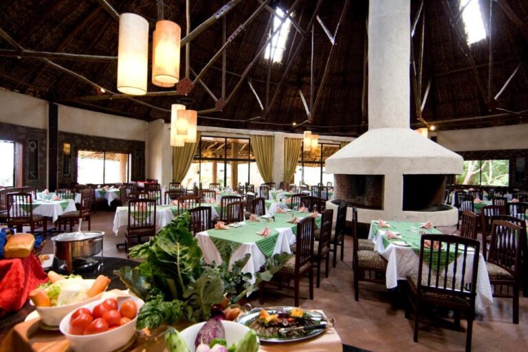 El restaurante, sus mesas con manteles verdes y un bufé de verduras en primer plano
