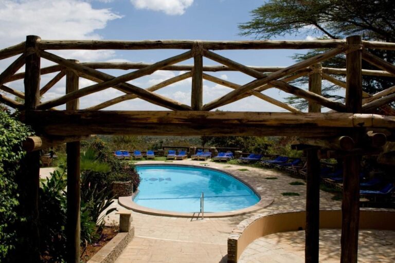 La piscina vista a través de una pérgola de troncos, rodeada de tumbonas