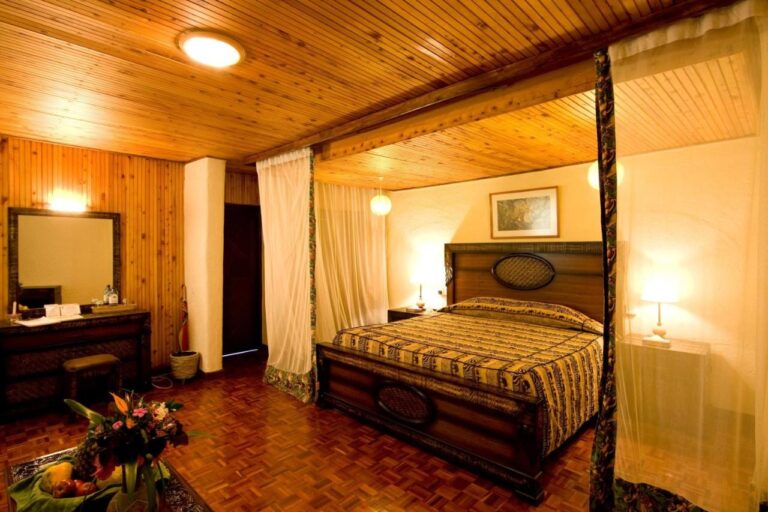 Una habitación con techo de madera, con una cama grande con dosel y un tocador