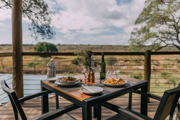 Una comida servida en una mesa de la terraza de madera, frente a la sabana