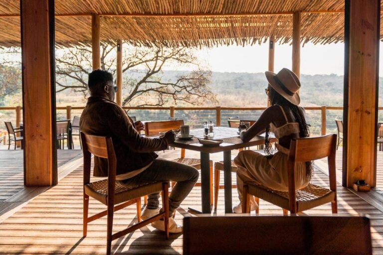 Una pareja a la mesa en la terraza cubierta del lodge, frente a la sabana