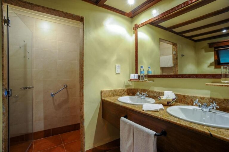 Un baño con dos lavabos y una ducha acristalada
