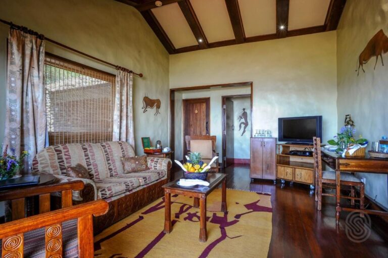 El salón de una suite, con un sofá estampado, una cesta de frutas y una televisión