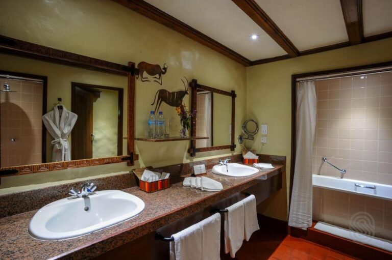 Un baño con dos lavabos, una bañera y un albornoz colgado
