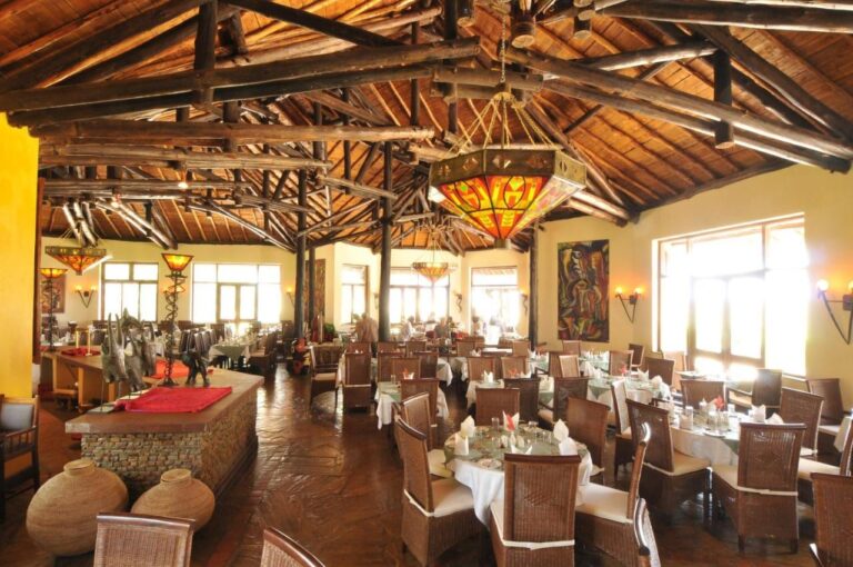 El comedor del restaurante bajo una estructura de troncos, con lámparas de vitral y mesas con manteles blancos