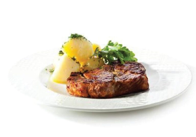 Una pieza de carne a la parrilla con papas y hierbas