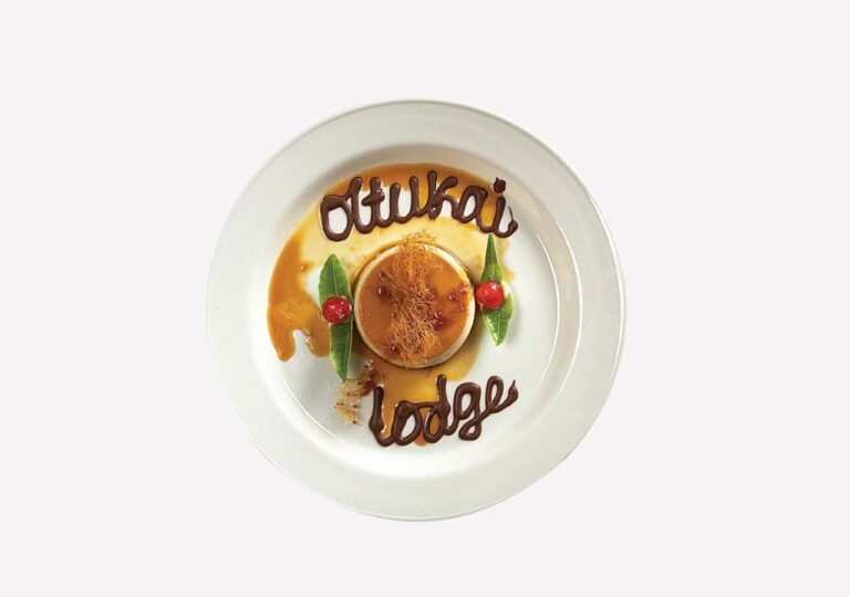 Un flan con caramelo, con Ol Tukai Lodge escrito con chocolate en el plato