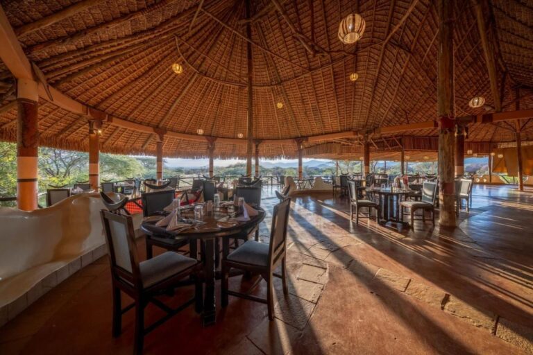 El comedor del restaurante bajo un inmenso techo de paja, abierto a las acacias y las colinas