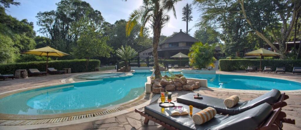 La piscina en forma de laguna del Sarova Mara Game Camp, alrededor de un islote de rocas con una palmera
