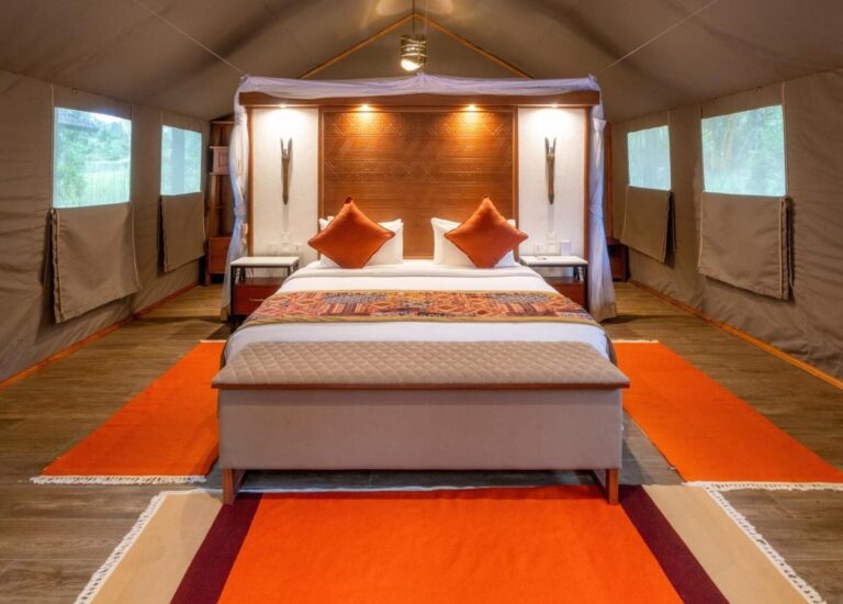 Una cama grande vista de frente, entre dos hileras de ventanas de lona