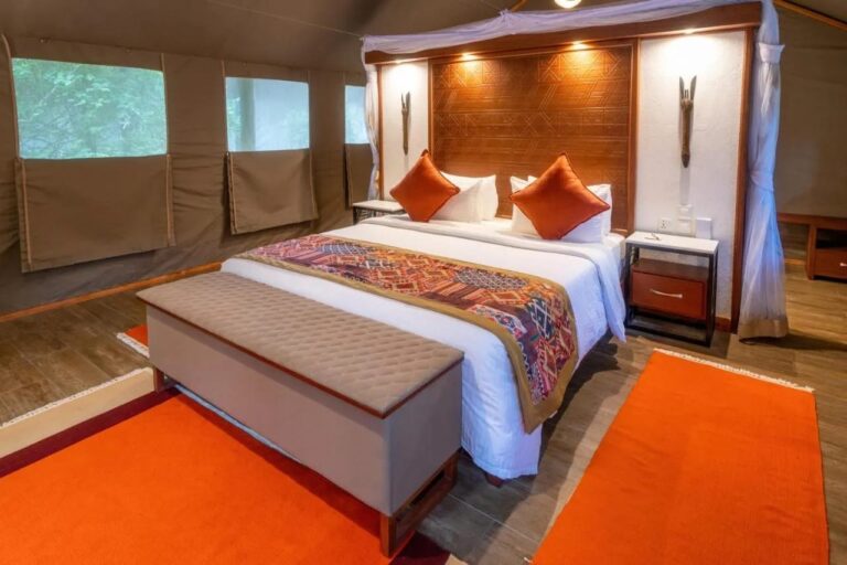 La cama de una tienda vista de lado, con su cabecero de madera y sus alfombras naranjas