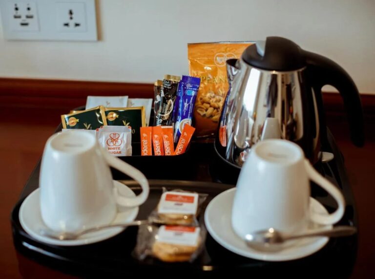Una bandeja con hervidor, dos tazas, té, café en sobres y galletas