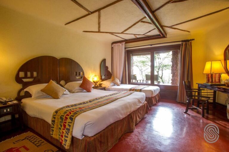 Una habitación con una cama grande y una individual de cabeceros de madera calada, y un escritorio junto a la ventana