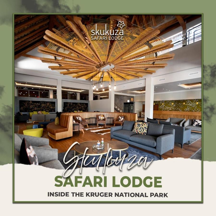 El salón del vestíbulo del Skukuza Safari Lodge bajo su techo de listones de madera en estrella, con el nombre del lodge escrito encima