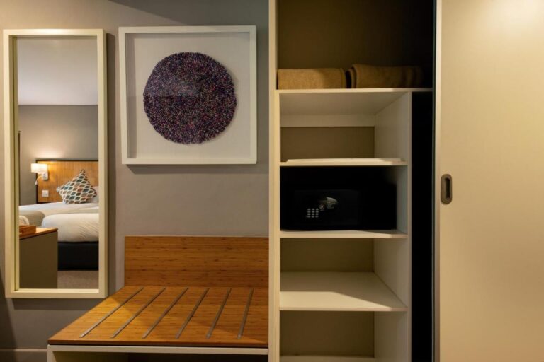 El armario de una habitación, con estantes, caja fuerte, portamaletas y espejo