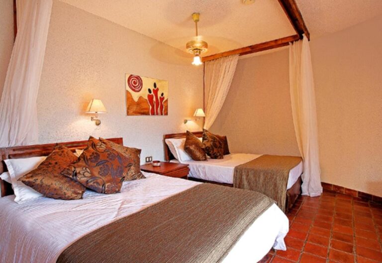 Una habitación con dos camas y cojines de motivos africanos