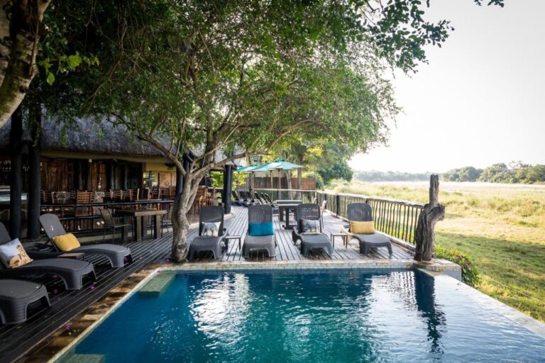 La piscina del Umkumbe Safari Lodge y su terraza de madera, sobre la orilla herbosa del río