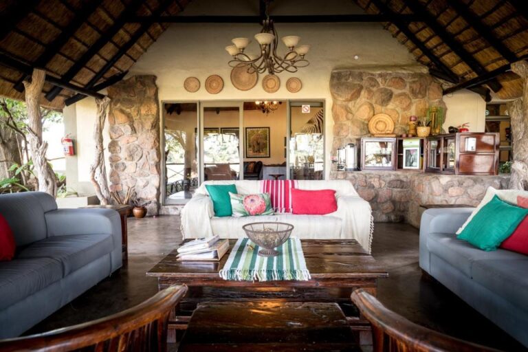 El salón abierto del Umkumbe Safari Lodge, bajo el techo de paja, con sofás grises y paredes de piedra