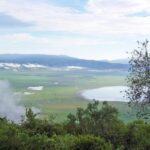 El fondo verde del cráter visto desde el borde, con el lago Magadi y nubes enganchadas a las paredes