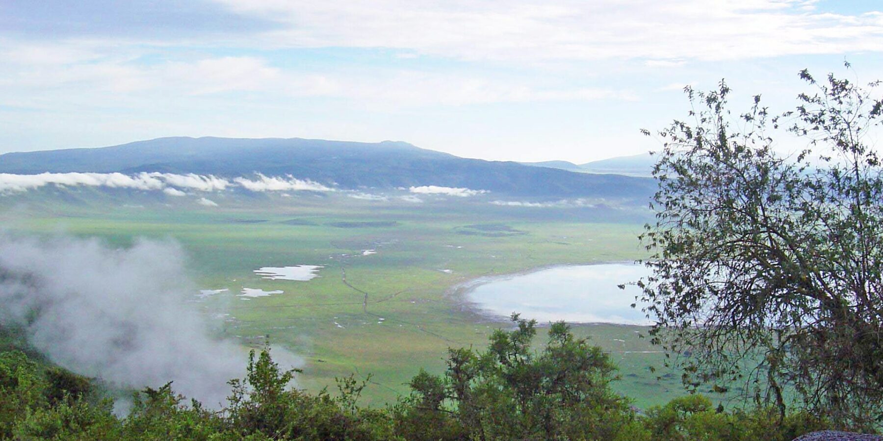 El fondo verde del cráter visto desde el borde, con el lago Magadi y nubes enganchadas a las paredes
